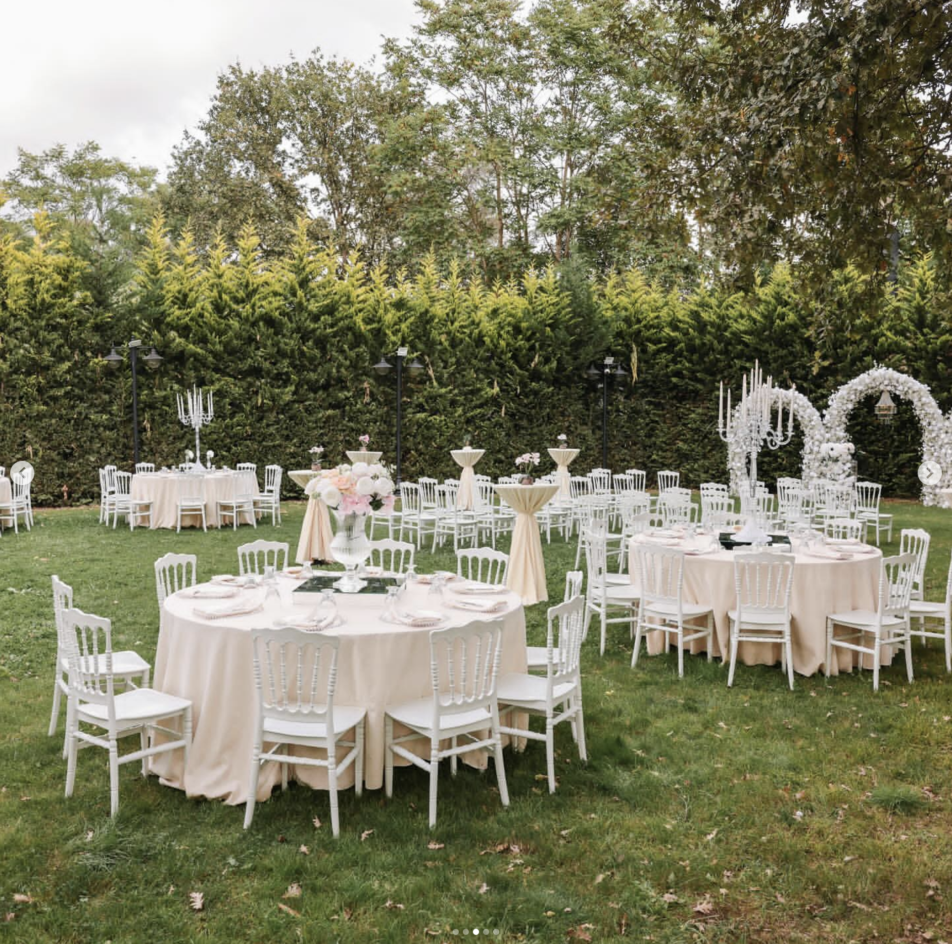 Reception setup with cream round tables, crystal candelabras and a floral arch backdrop