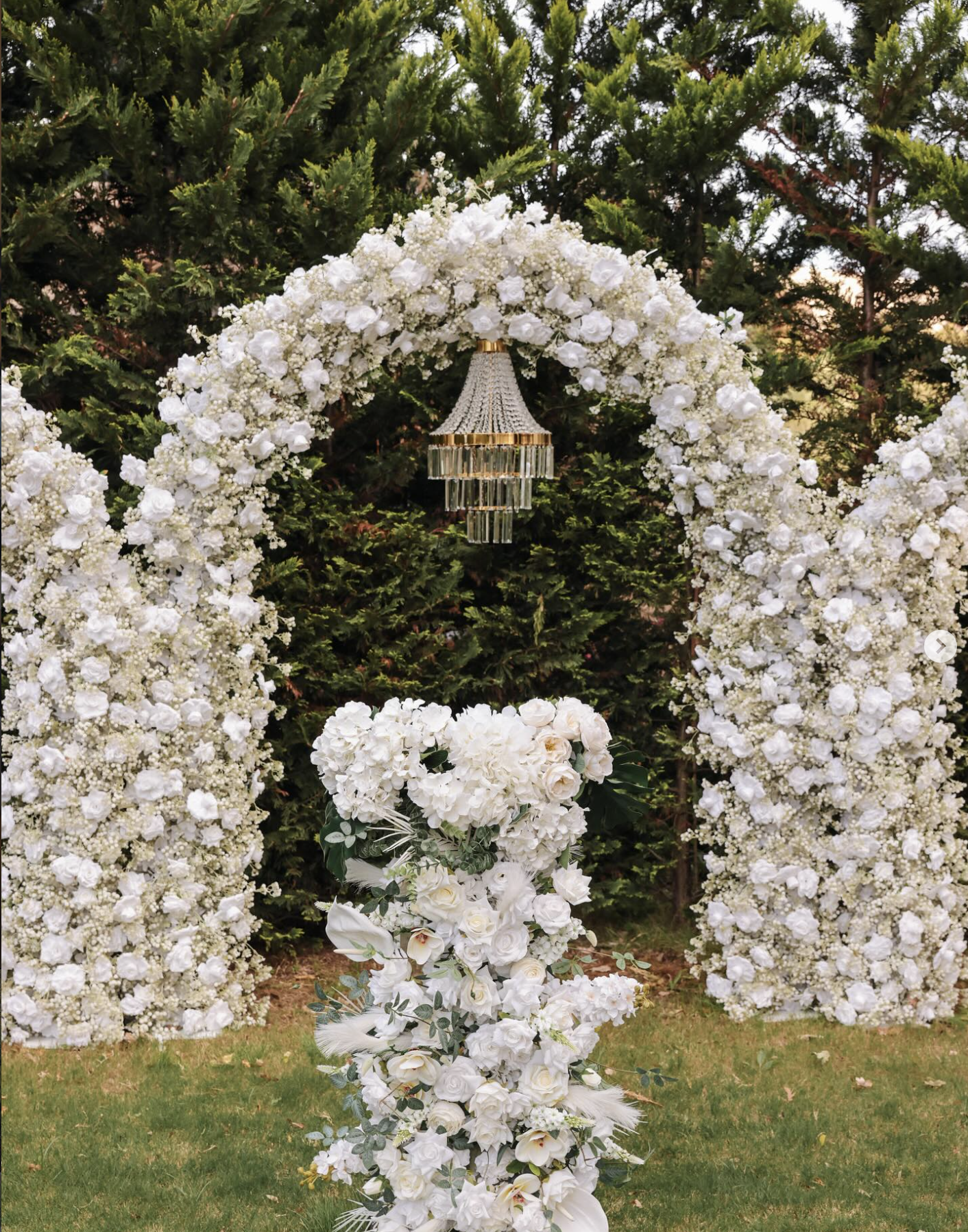Close-up of a lavish white floral arch with a hanging crystal chandelier